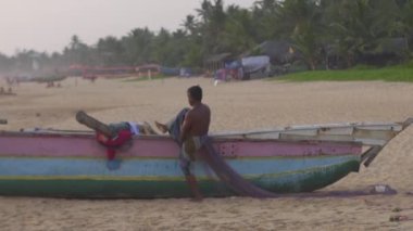 Hikkaduwa, Sri Lanka, 1.12.2020 - Sri Lankalı balıkçı renkli tekneye bindi