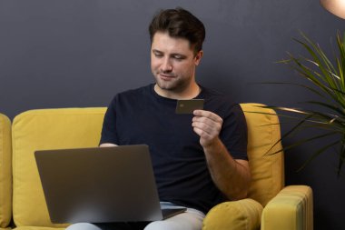 Adam internetten alışveriş ya da ödeme yapıyor. Kredi kartı CVV güvenlik koduna bakıyor.