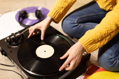 Kız elleri pikaba plak koyar. Vinil plak çalarla evde uzanıyorsun.