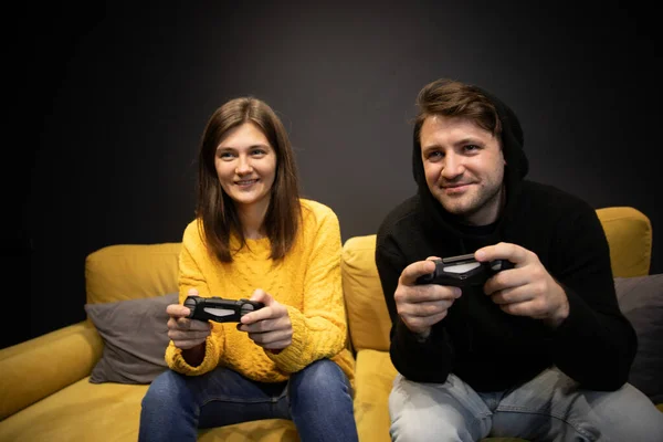 Sourire désinvolte habillé couple jouer à des jeux vidéo tenant joysticks console — Photo