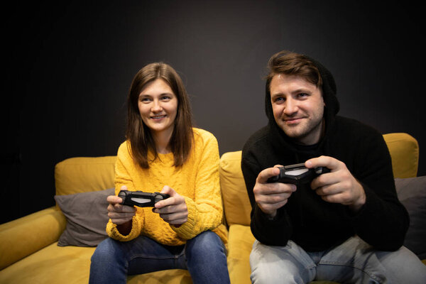 улыбающаяся пара, играющая в видеоигры с консольными джойстиками