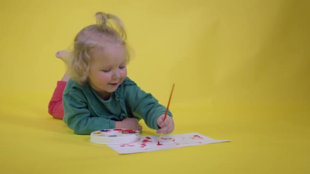 Чарівна дівчинка-малюк Підбирає фарбу на палітрі і малює щасливу дитячу картину — стокове відео