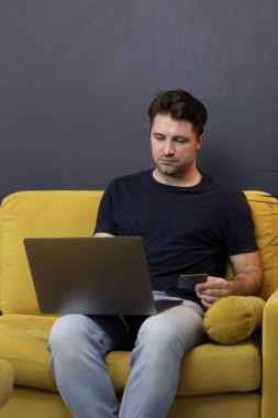 Adam internetten alışveriş ya da ödeme yapıyor. Kredi kartı CVV güvenlik koduna bakıyor.