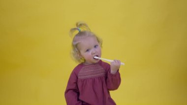 Kiraz rengi elbiseli şirin bir kız. Dişlerini fırçalarken komik.