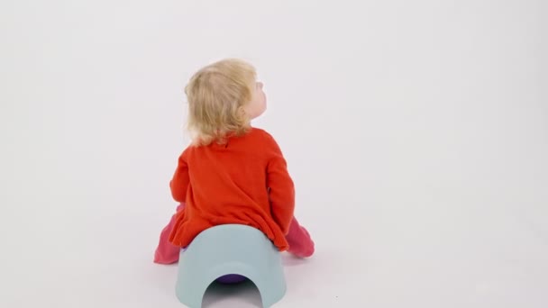 Μικρό μωρό κάθεται πίσω σε παιδικό γιογιό σε απομονωμένο λευκό φόντο, κατούρημα — Αρχείο Βίντεο
