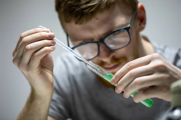 Bebaarde bioloog in bril voert chemisch experiment met groene reagens — Stockfoto