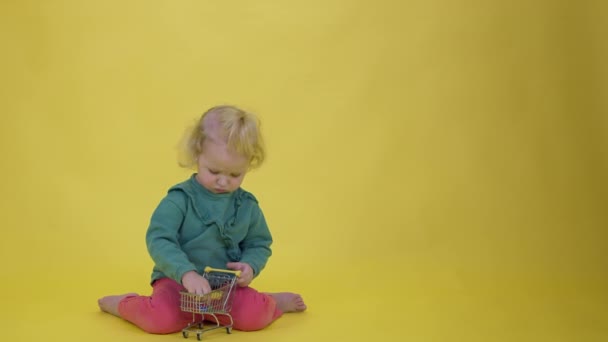 Aranyos mosolygós kisbaba lány játszik ügyfél játék szupermarket kosár — Stock videók