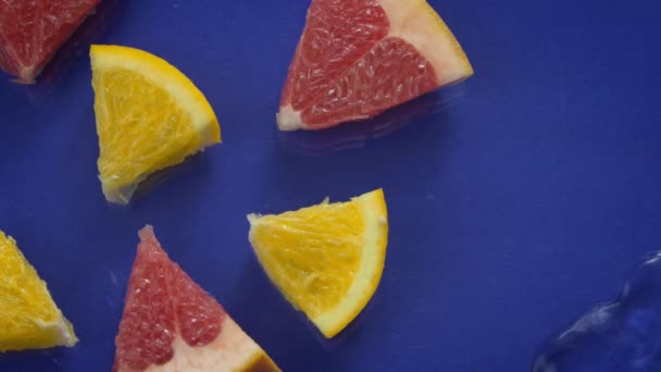 青い背景に水のスプラッシュで新鮮な柑橘類のジュース片、トップビュー — ストック動画