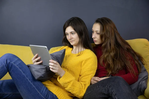 Two pretty girls make purchases or payments online using tablet Couch shopping Stock Picture
