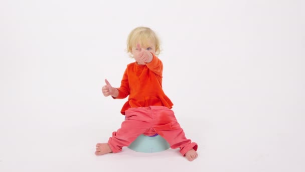 Roztomilý šťastný veselý batole dívka sedí na nočník ukazující palce nahoru gesto — Stock video