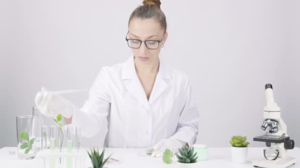 Vrouwelijke biochemische onderzoeker druppelt vloeibaar reagens op blad van GGO-plant in lab — Stockvideo