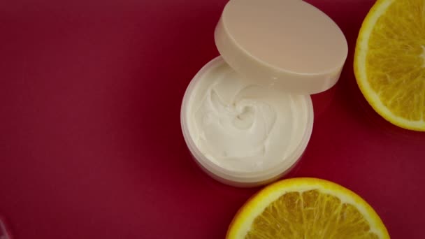 Water stromend slow mo op pot beauty cream met open deksel en sinaasappelschijfjes — Stockvideo