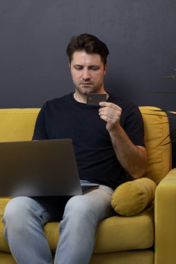 Adam internetten alışveriş ya da ödeme yapıyor. Kredi kartı CVV güvenlik koduna bakıyor.