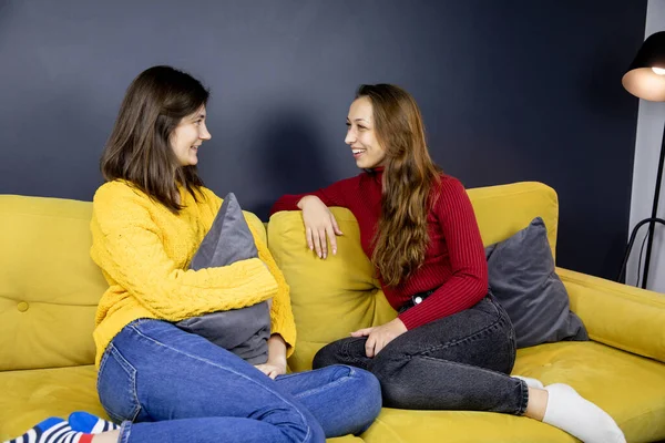 Joven lesbiana pareja sentarse en cómodo sofá rodillas doblado hablando alegremente riendo — Foto de Stock