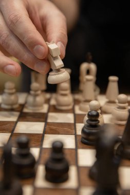 Satranç oyununda bir sonraki adımı atan el. İnsan eli, tahta beyaz şövalyeyi hareket ettiriyor.