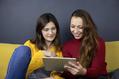 Genç lezbiyen çift internetten tablet seçici kıyafetler kullanarak e-ticaret alışverişi yapıyor.