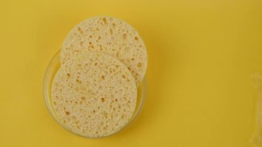 Kozmetik temizleyiciler, sarı arka planda su sıçratan yüz temizleyicileri.