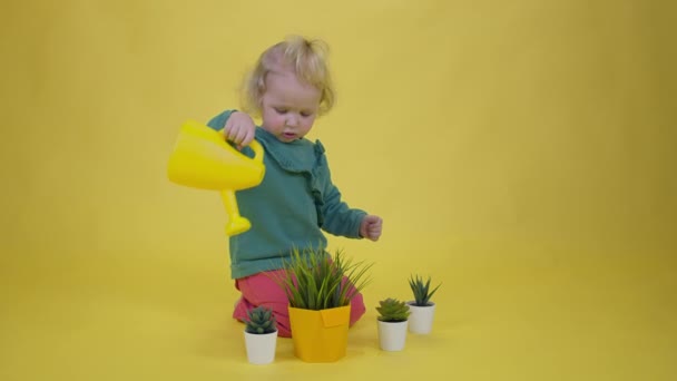 따듯하게 웃고 있는 귀여운 아기가 물통에서 꽃을 흔들고 있는 모습 — 비디오