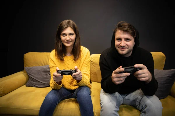 Souriant désinvolte habillé jeune couple concentré sur jouer à un jeu vidéo à la maison — Photo