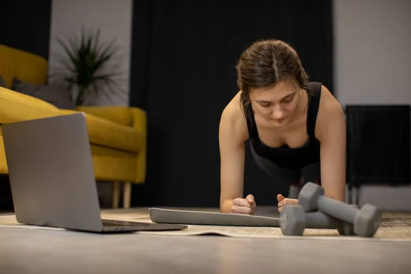 Mujer joven disfruta del entrenamiento culturismo abs ejercicio, se para en tablón interior — Foto de Stock