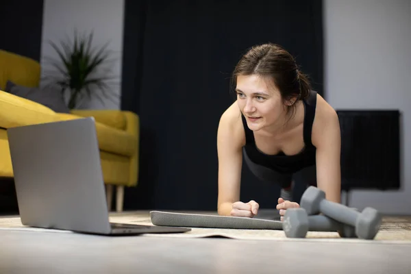 Sonriente chica se para en tablón en el suelo mirando a la computadora portátil contar segundos — Foto de Stock