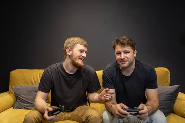Deux gais beaux gars jouent passionnément jeu vidéo tenant manette de jeu console — Photo