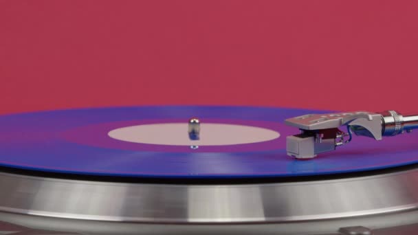 Blue vinyl record spinning on turntable isolated on red. LP player in motion — Stock Video