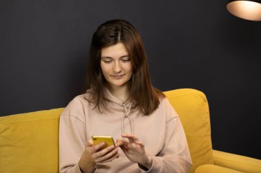 Çekici, uzun saçlı esmer kız. Akıllı telefondan konuşup mesajlaşıyor.