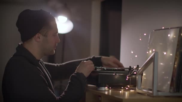 Неосвічений красивий хлопець ставить записи на поворотний стіл прослуховування музики в навушниках — стокове відео