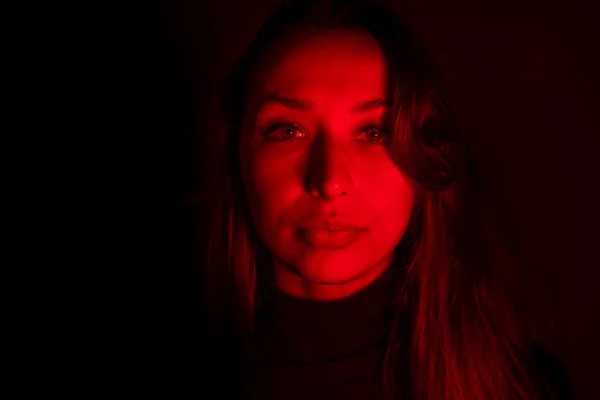 Mujer joven mira a la cámara en contraste luz roja, adicción, encarcelamiento — Foto de Stock