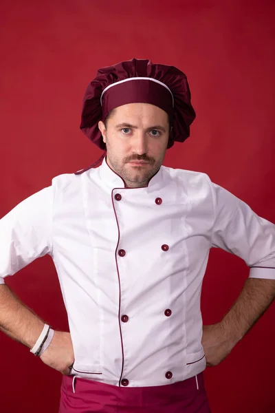 Retrato de chef guapo serio en uniforme sobre fondo rojo aislado —  Fotos de Stock