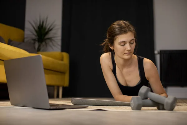 Pensativo Lazy Girl en ropa deportiva acostado en la esterilla de yoga mirando el teléfono inteligente — Foto de Stock