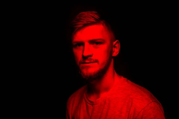 Portrait de beau mec regarde la caméra en studio sombre avec la foudre au néon rouge — Photo