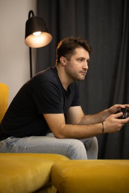 Oyunlara kafayı takmış adam elinde oyun konsolu tutuyor.