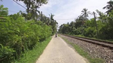 Galle, Sri Lanka, 1.12.2020 - Kız turist tren yolu boyunca scooter sürüyor