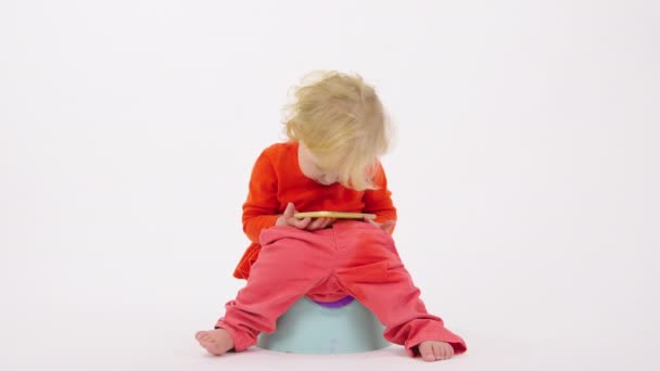 Funny girl toddler se sienta en los niños orinal explorar teléfono inteligente sobre fondo blanco — Vídeo de stock