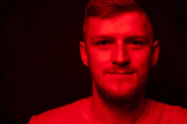 Portrait of smiling man looks friendly at camera in contrast red light, person — Stock Photo, Image