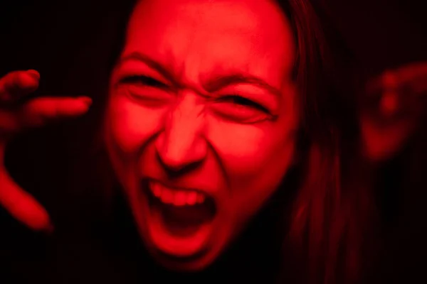 Mujer gritando de cerca a la cámara en luz de neón roja, cara furiosa, histérica — Foto de Stock
