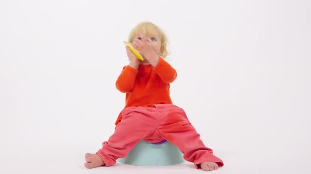 可爱而快乐的小女孩坐在便盆上，用智能手机说话 — 图库视频影像