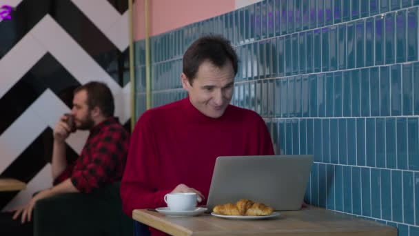 Stilig medelålders man meddelande och chatta sitter med bärbar dator i caféet — Stockvideo