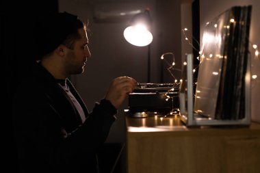 Genç, tıraşsız yakışıklı hippi tonkollarını pikapta plağa takıyor.