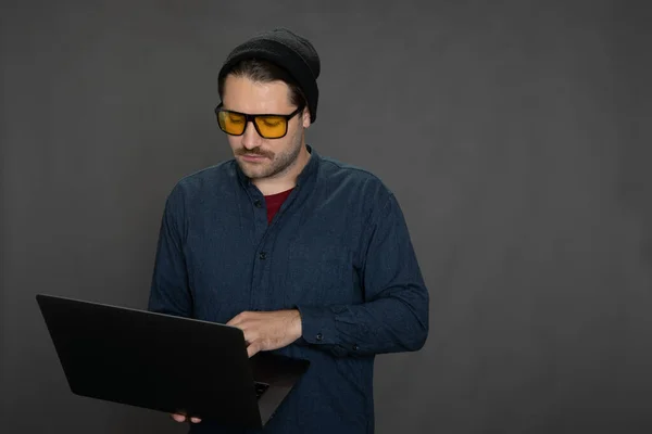 Hipster guy working with laptop, dark background, copy space, business education