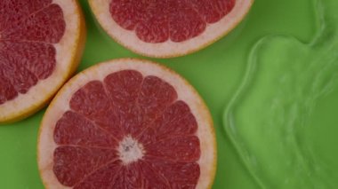 Kristal berrak su yavaş akıyor greyfurt dilimleri açık yeşil zemin üzerinde