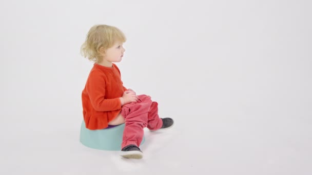 Капризная уставшая сонная девочка сидит на горшке и говорит родителям, чтобы они приносили игрушки. — стоковое видео