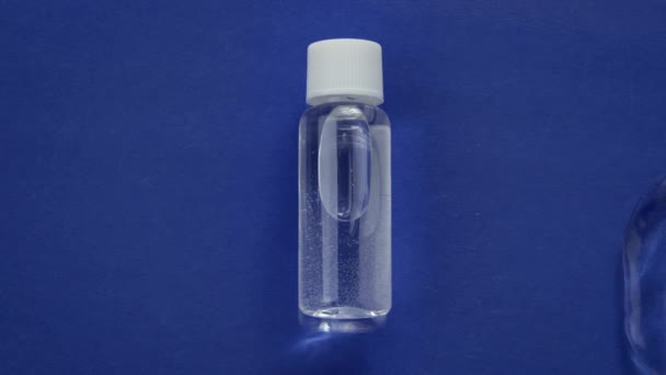 Cosmetische fles met water tonic in water spatten op blauwe achtergrond. Bovenaanzicht — Stockvideo
