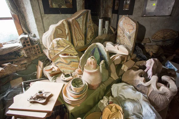 Ceramic artist artwork in picturesque mess of dusty and dirty pottery workshop