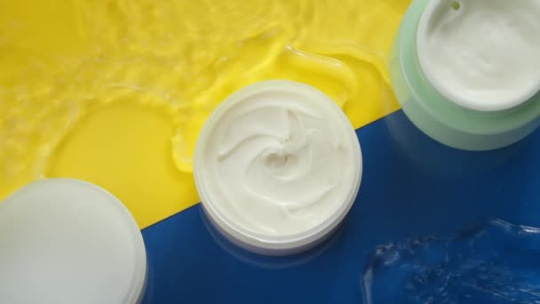 Kozmetikai edények hidratáló krém tiszta vízben fröccsenő színes háttér — Stock videók