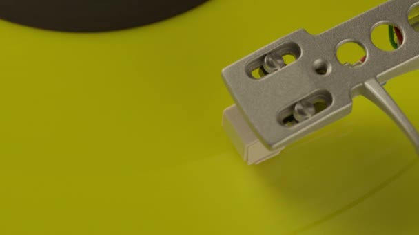 Close-up pickup head on yellow vinyl record spinning on turntable. Top view — Stock Video