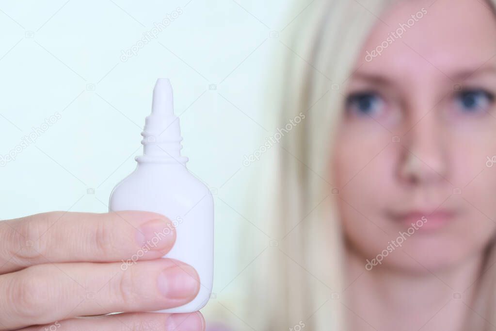 A bottle of nasal spray in a hand of a woman close up, allergy, viral and bacterial rhinitis and sinusitis treatment.