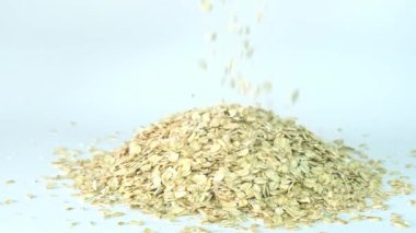 Çiğ yulaf ezmesi beyaz arka plana dökülüyor. Sağlıklı yulaf lapası malzemesi.